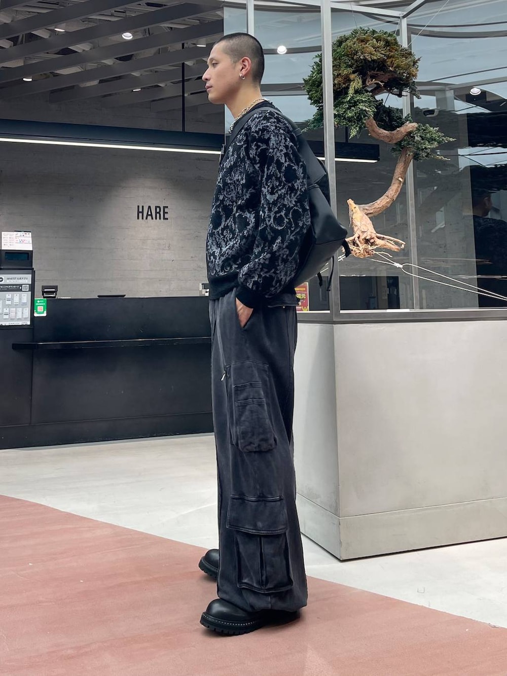 グレー系のニット/セーター、ブラック系のメッセンジャーバッグ、ブラック系のスウェットパンツを着用したメンズの秋コーディネートの2枚目の写真