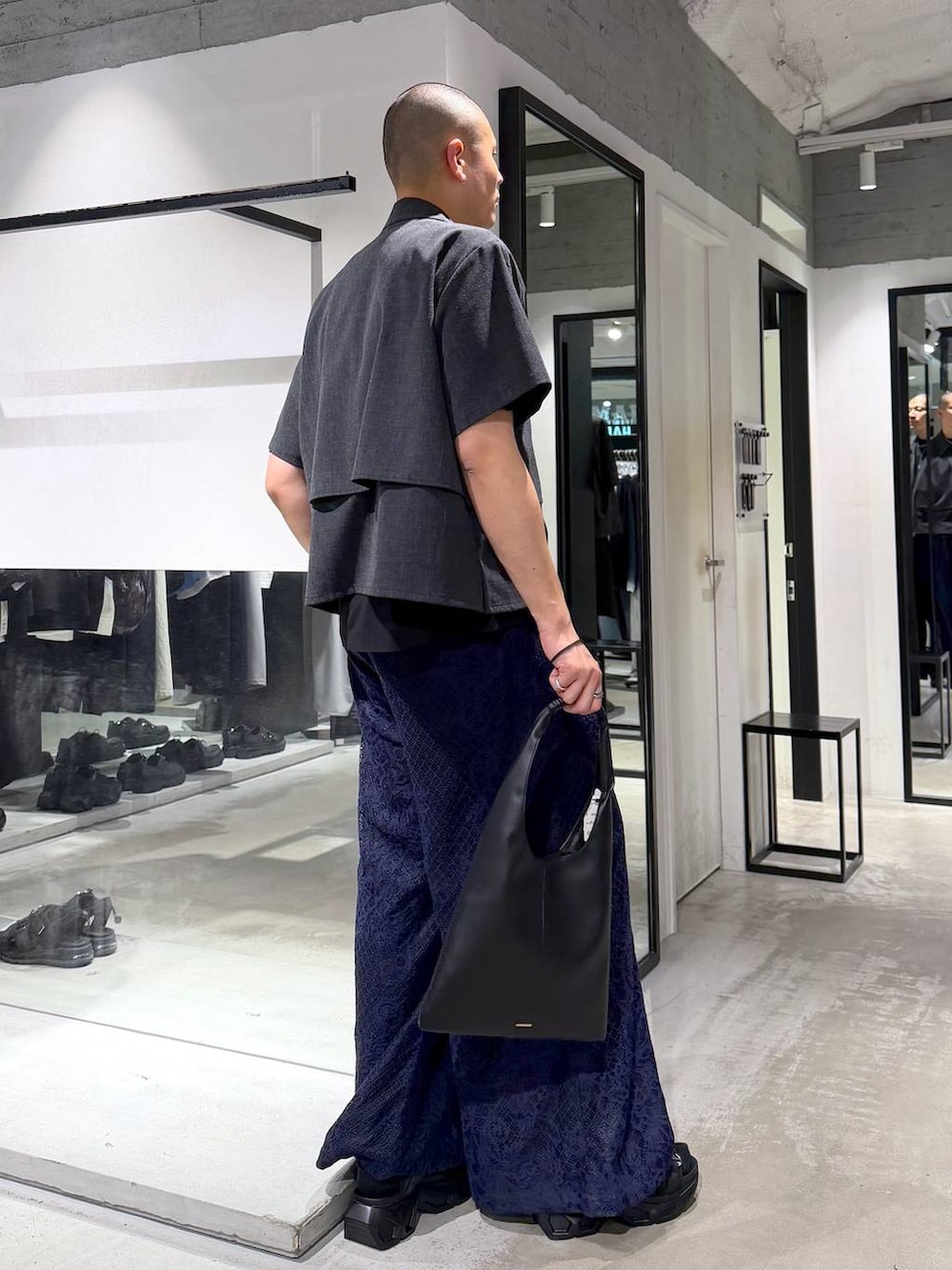 ブラック系のトートバッグ、ブラック系のサンダル、ブルー系のスラックスを着用したメンズの春コーディネートの4枚目の写真