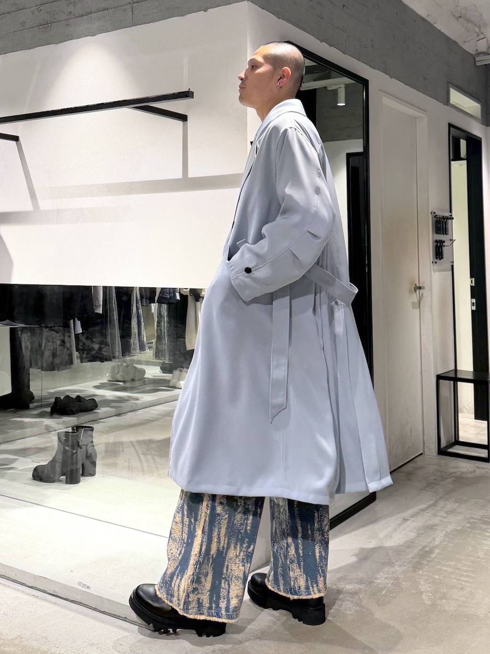 ブラック系のドレスシューズ、ブラック系のハンドバッグ、グリーン系のトレンチコートを着用したメンズの冬コーディネートの2枚目の写真