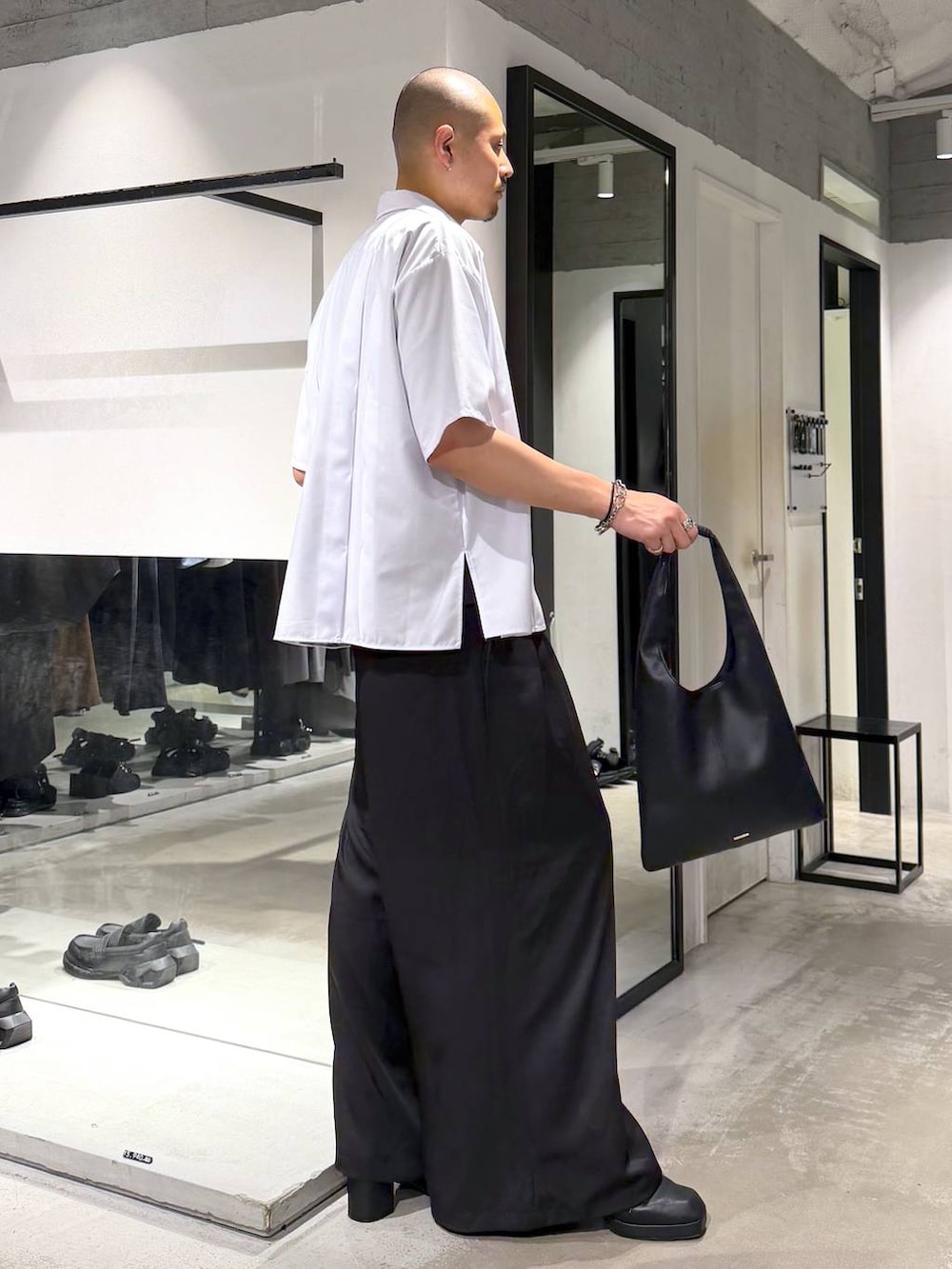 ブラック系のトートバッグ、ブラック系のサンダル、ブルー系のTシャツ/カットソーを着用したメンズの夏コーディネートの4枚目の写真