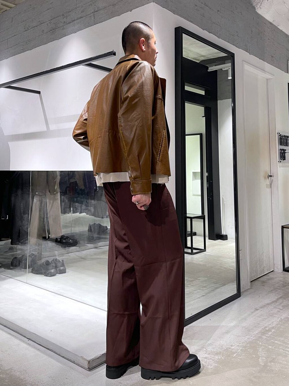 レッド系のスラックス、ブラック系のドレスシューズ、ブラック系のニット/セーターを着用したメンズの冬コーディネートの4枚目の写真