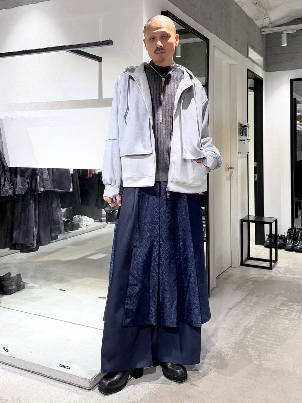グレー系のニット/セーター、ブラック系のブーツ、ブルー系のその他パンツを着用したメンズの秋コーディネートの5枚目の写真