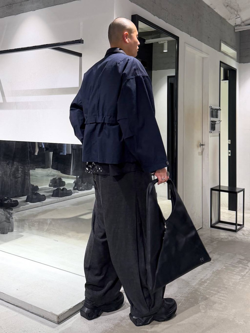 ブラック系のスニーカー、ブラック系のスラックス、ブラック系のトートバッグを着用したメンズの春コーディネートの4枚目の写真