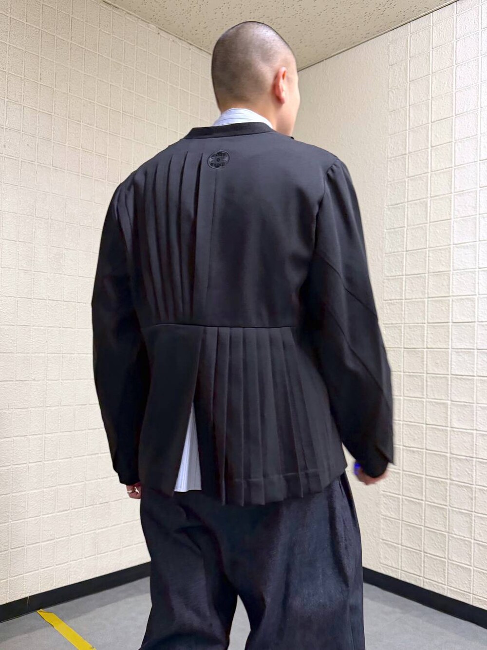 ブラック系のノーカラージャケット、ブルー系のデニムパンツを着用したメンズの春コーディネートの8枚目の写真