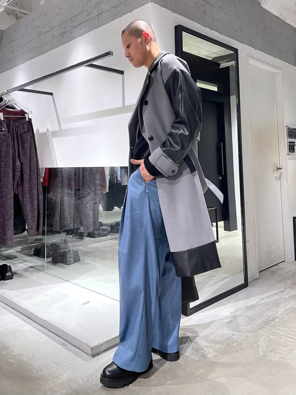 グレー系のトレンチコート、ブラック系のトートバッグ、ブラック系のニット/セーターを着用したメンズの冬コーディネートの2枚目の写真