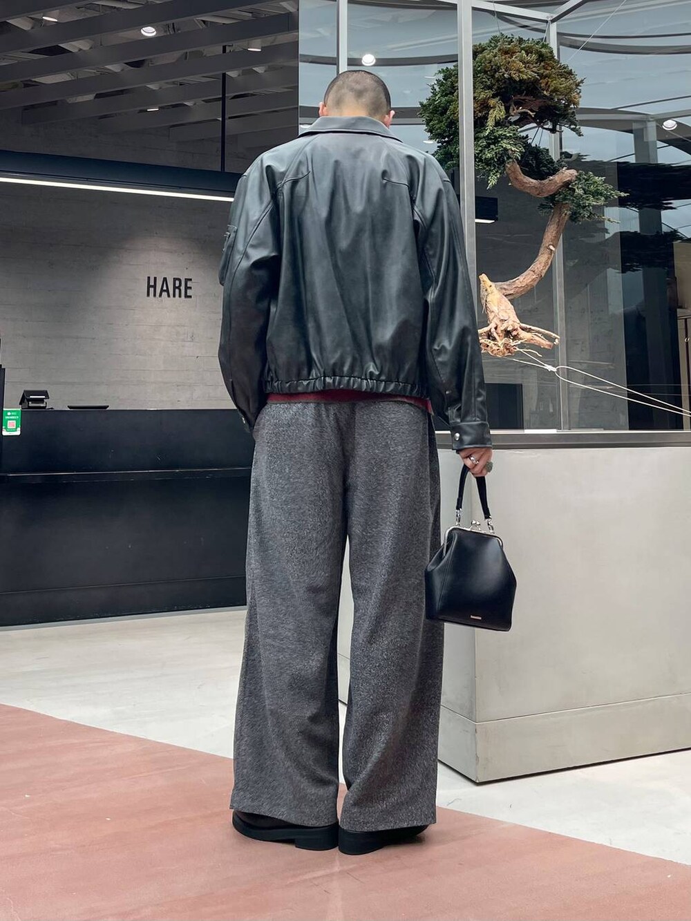 グレー系のブルゾン、ブラック系のローファー、ブラック系のスラックスを着用したメンズの秋コーディネートの3枚目の写真