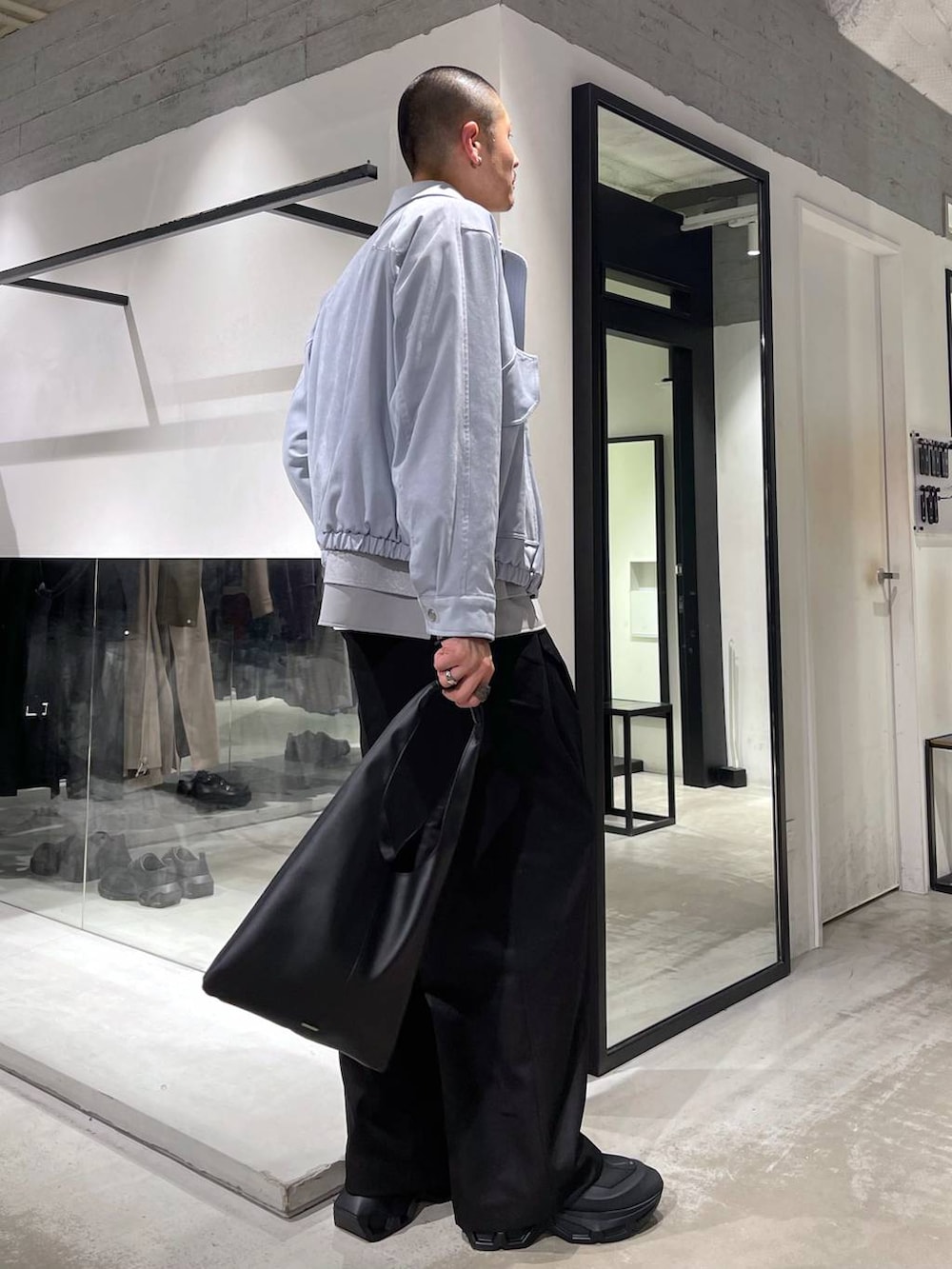 ブラック系のトートバッグ、ブルー系のブルゾン、グレー系のシャツ/ブラウスを着用したメンズの冬コーディネートの4枚目の写真