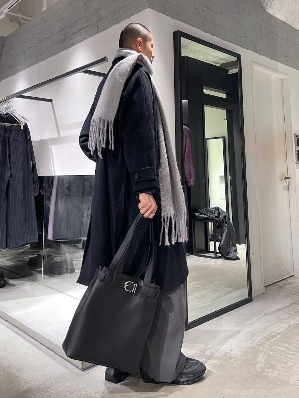 ブラック系のステンカラーコート、ブルー系のカーディガン/ボレロ、ブラック系のトートバッグを着用したメンズの冬コーディネートの4枚目の写真