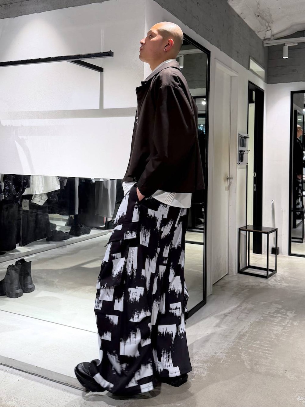 ブラック系のスニーカー、ホワイト系のシャツ/ブラウス、ブラウン系のブルゾンを着用したメンズの春コーディネートの2枚目の写真