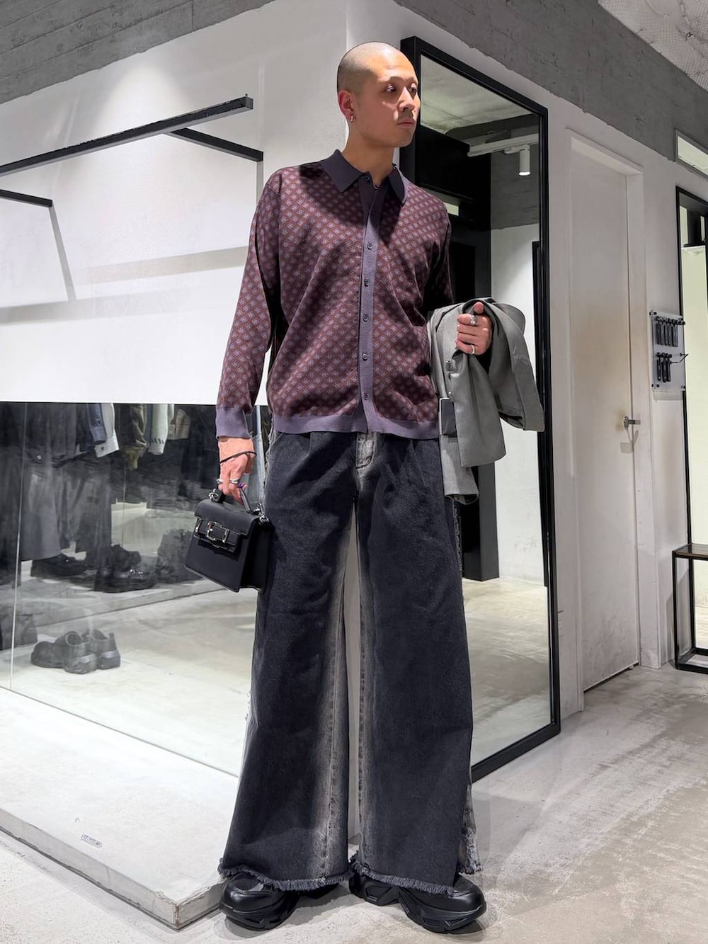 ブラック系のスニーカー、ブラック系のハンドバッグ、ブラック系のデニムパンツを着用したメンズの冬コーディネートの5枚目の写真