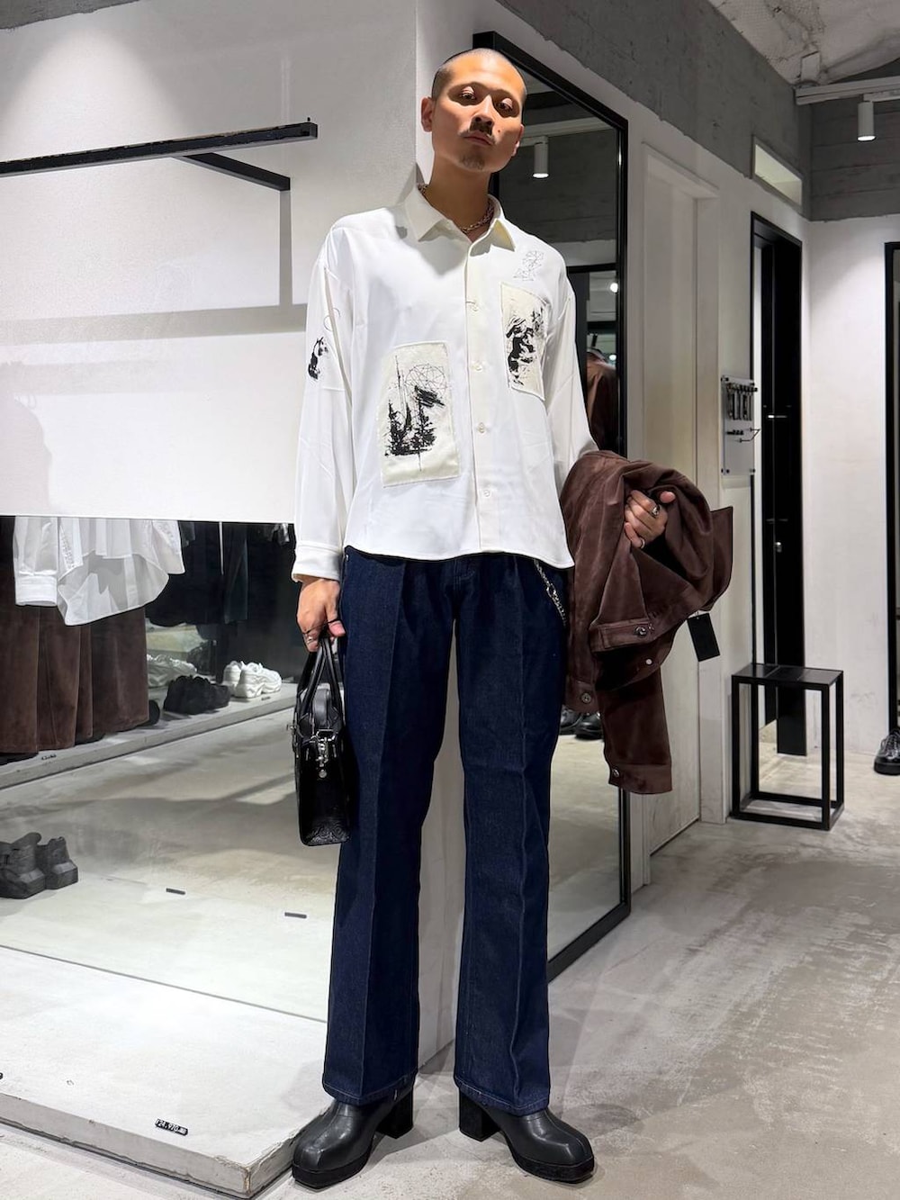 ブラック系のボストンバッグ、ブラック系のブーツ、ブルー系のデニムパンツを着用したメンズの秋コーディネートの5枚目の写真