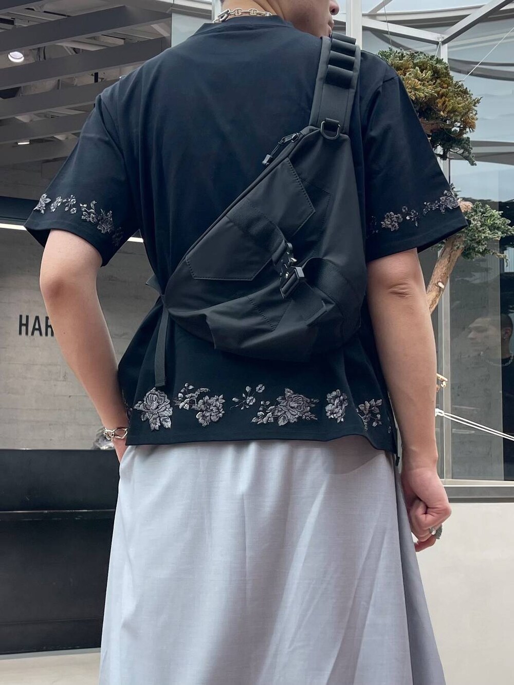 グレー系のスラックス、ブラック系のサンダル、ブラック系のTシャツ/カットソーを着用したメンズの春コーディネートの2枚目の写真