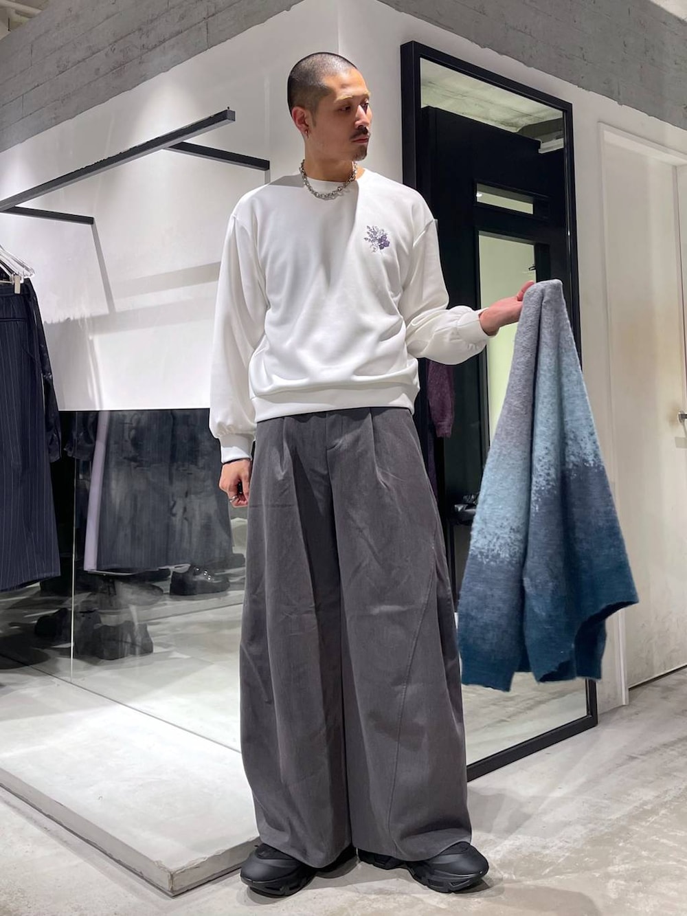 ブラック系のステンカラーコート、ブルー系のカーディガン/ボレロ、ブラック系のトートバッグを着用したメンズの冬コーディネートの7枚目の写真