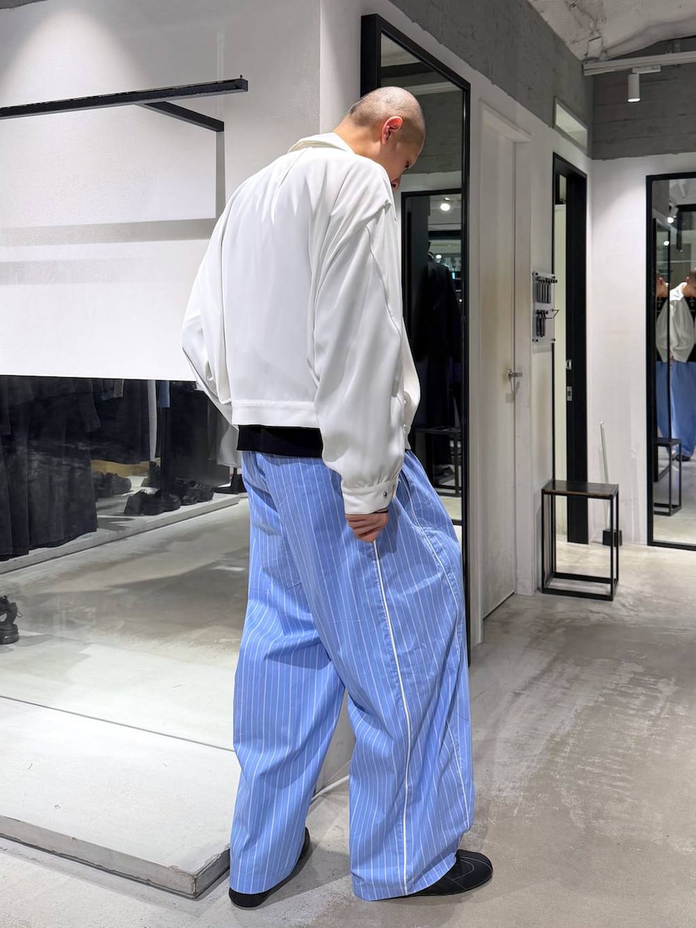 ホワイト系のブルゾン、ブルー系のスラックス、ブラック系のニット/セーターを着用したメンズの春コーディネートの4枚目の写真