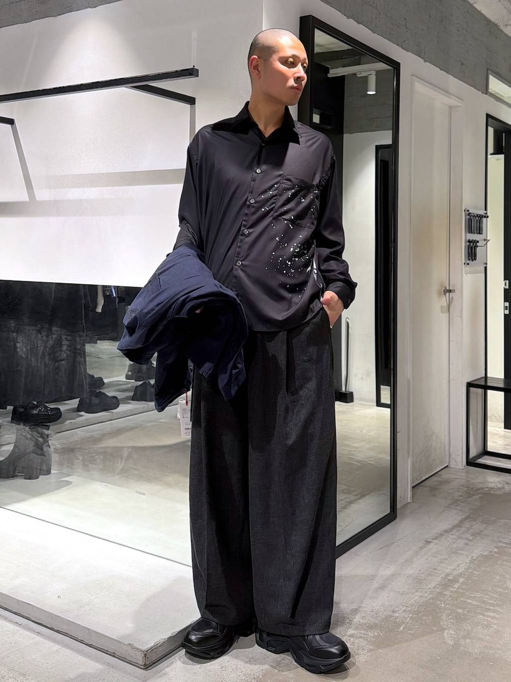 ブラック系のスニーカー、ブラック系のスラックス、ブラック系のトートバッグを着用したメンズの春コーディネートの7枚目の写真