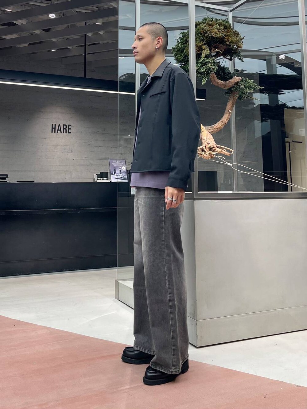 ブラック系のローファー、ブラウン系のデニムパンツ、ブラック系のショルダーバッグを着用したメンズの秋コーディネートの2枚目の写真