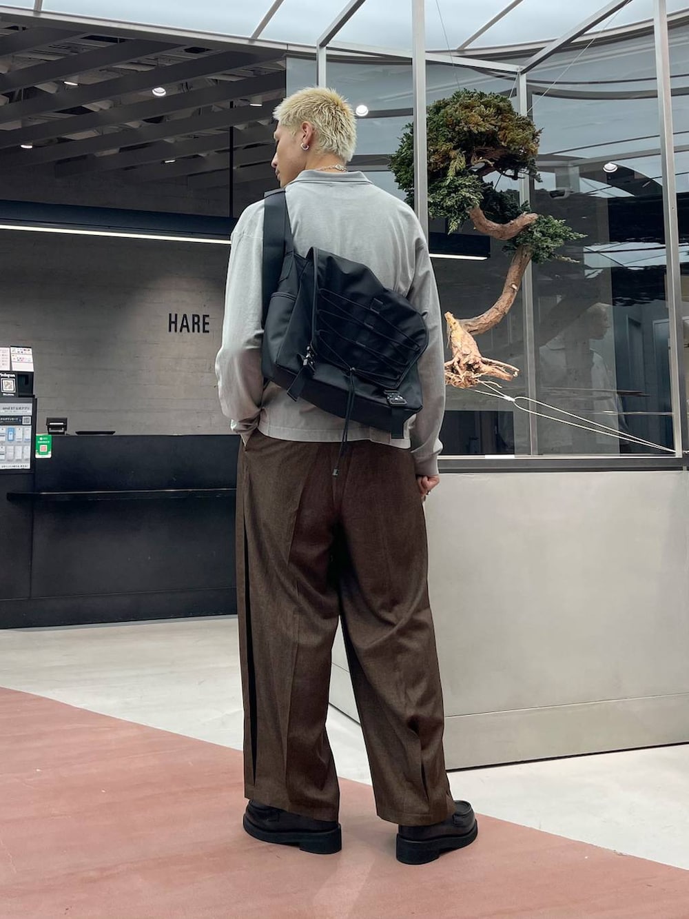 ブラウン系のスラックス、ブラック系のメッセンジャーバッグ、ブラック系のローファーを着用したメンズの秋コーディネートの2枚目の写真