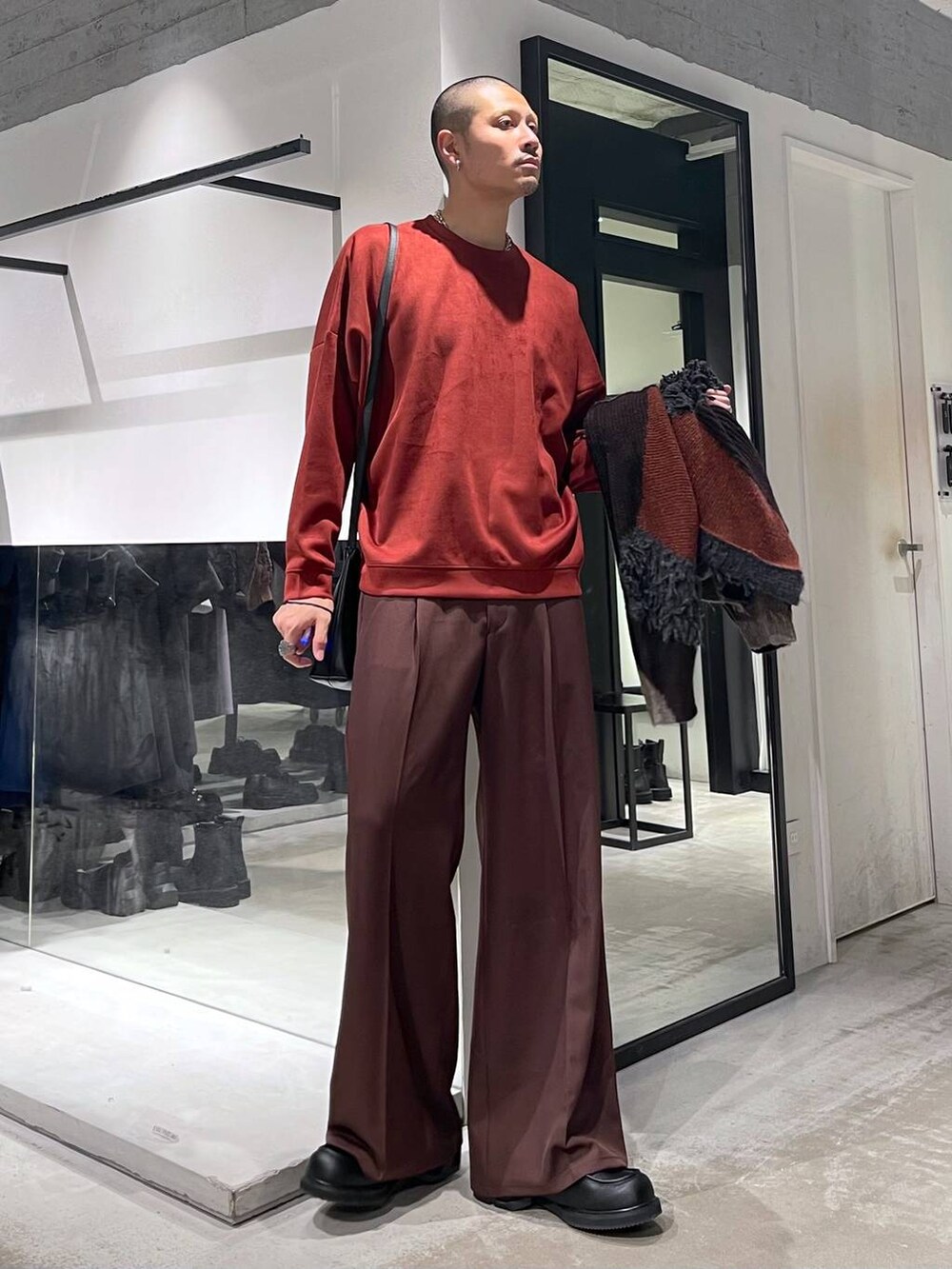 オレンジ系のスウェット、レッド系のスラックス、ブラック系のローファーを着用したメンズの冬コーディネートの2枚目の写真