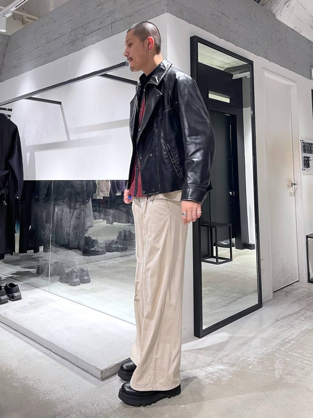 ベージュ系のスラックス、レッド系のシャツ/ブラウス、ブラック系のショルダーバッグを着用したメンズの冬コーディネートの2枚目の写真