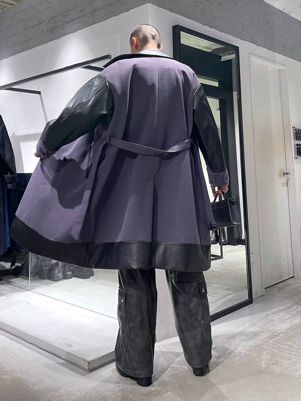 パープル系のトレンチコート、グレー系のカーゴパンツ、ブラック系のブーツを着用したメンズの冬コーディネートの3枚目の写真