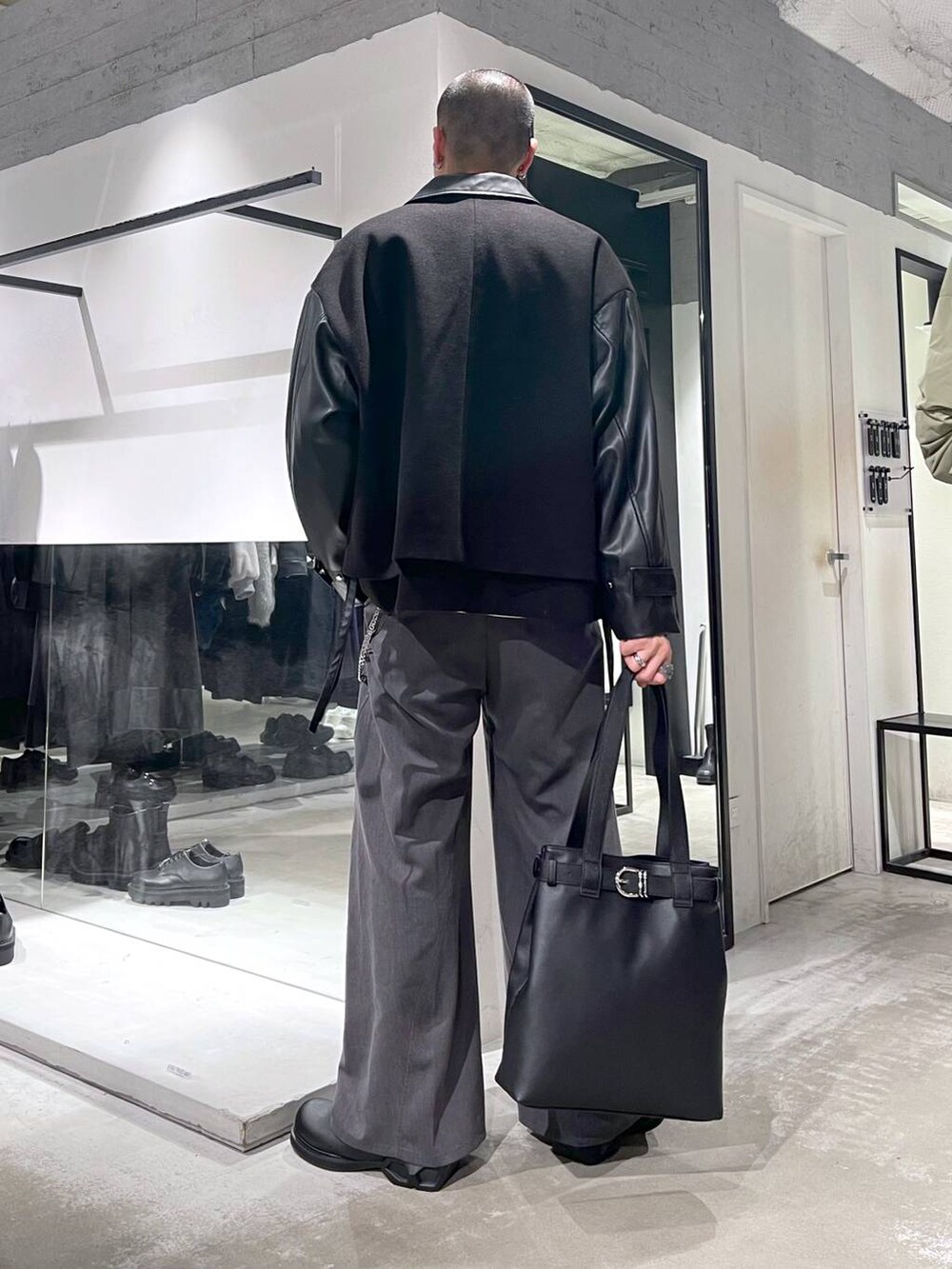 ブラック系のブルゾン、ブラック系のトートバッグ、グレー系のスラックスを着用したメンズの秋コーディネートの3枚目の写真