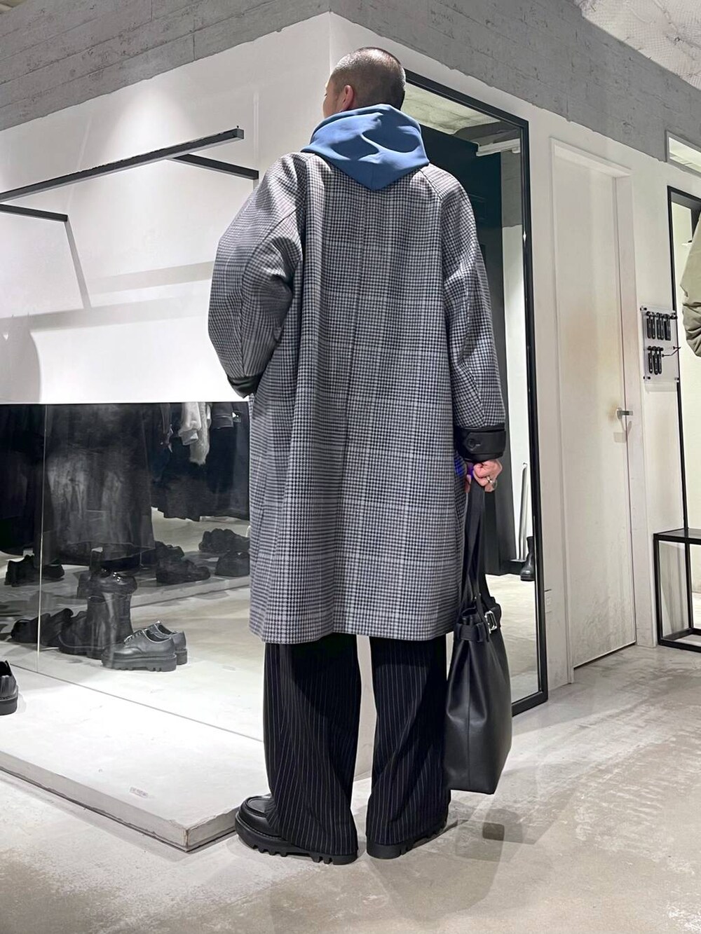 ベージュ系のステンカラーコート、ブラック系のトートバッグ、ブラック系のドレスシューズを着用したメンズの秋コーディネートの3枚目の写真