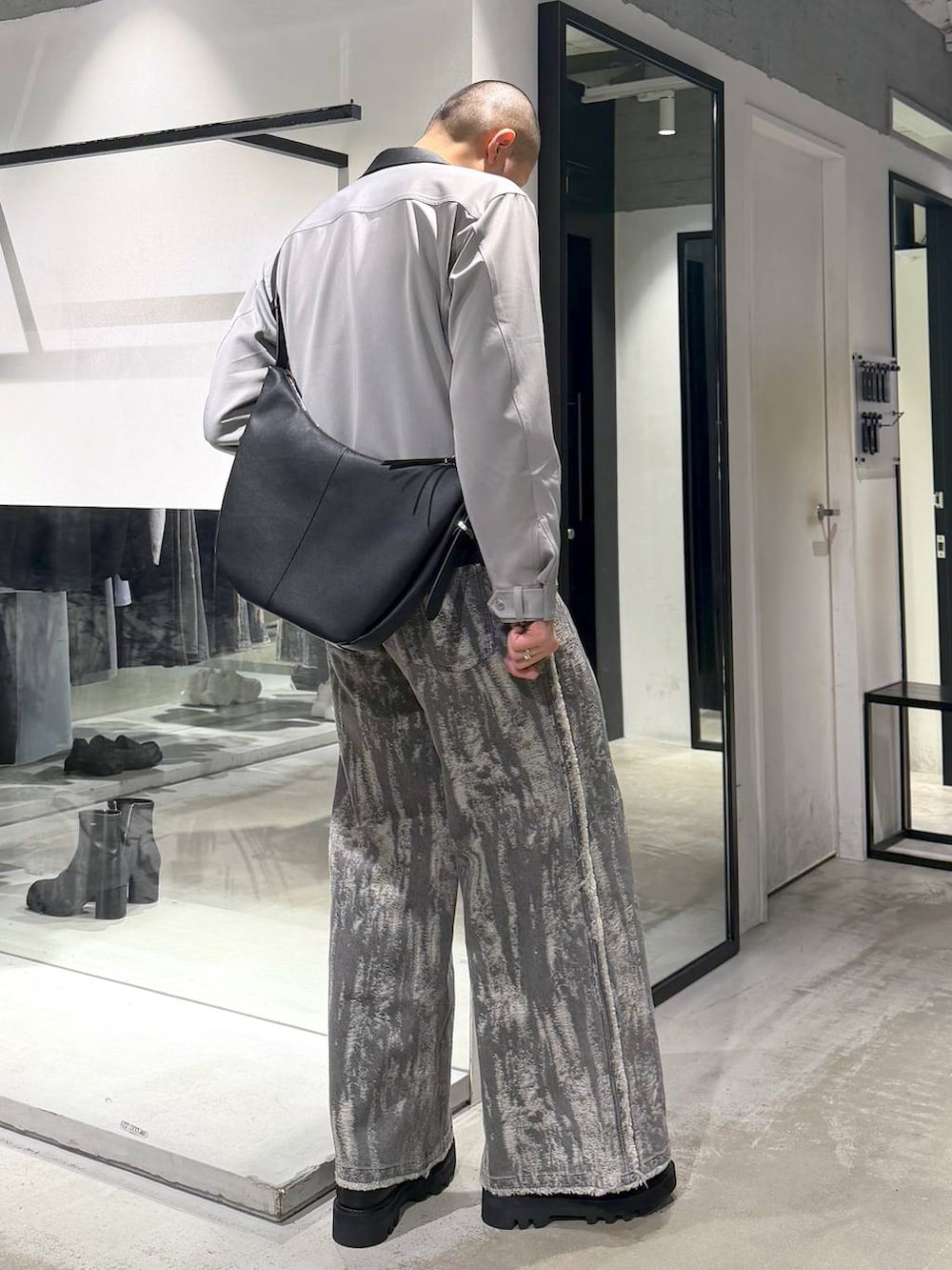 ブラック系のドレスシューズ、ブラック系のショルダーバッグ、グレー系のデニムパンツを着用したメンズの春コーディネートの4枚目の写真