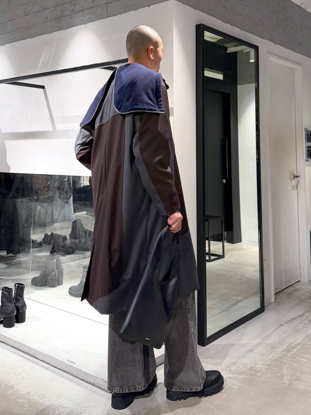 ブラック系のトートバッグ、ブラウン系のデニムパンツ、ブラック系のドレスシューズを着用したメンズの冬コーディネートの3枚目の写真