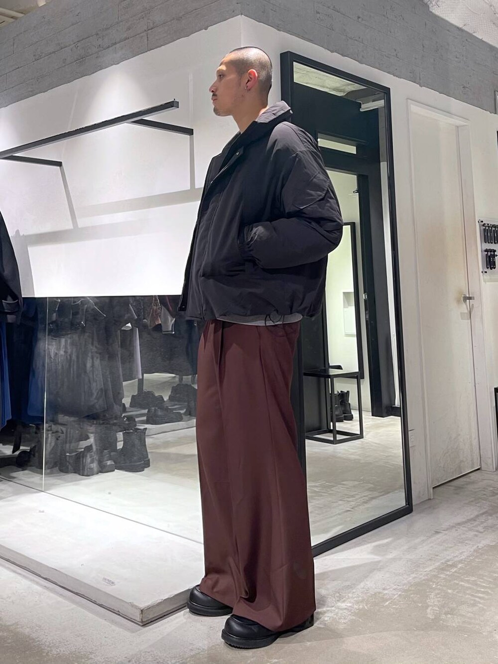 グレー系のニット/セーター、ブラック系のダウンジャケット/コート、レッド系のスラックスを着用したメンズの冬コーディネートの2枚目の写真