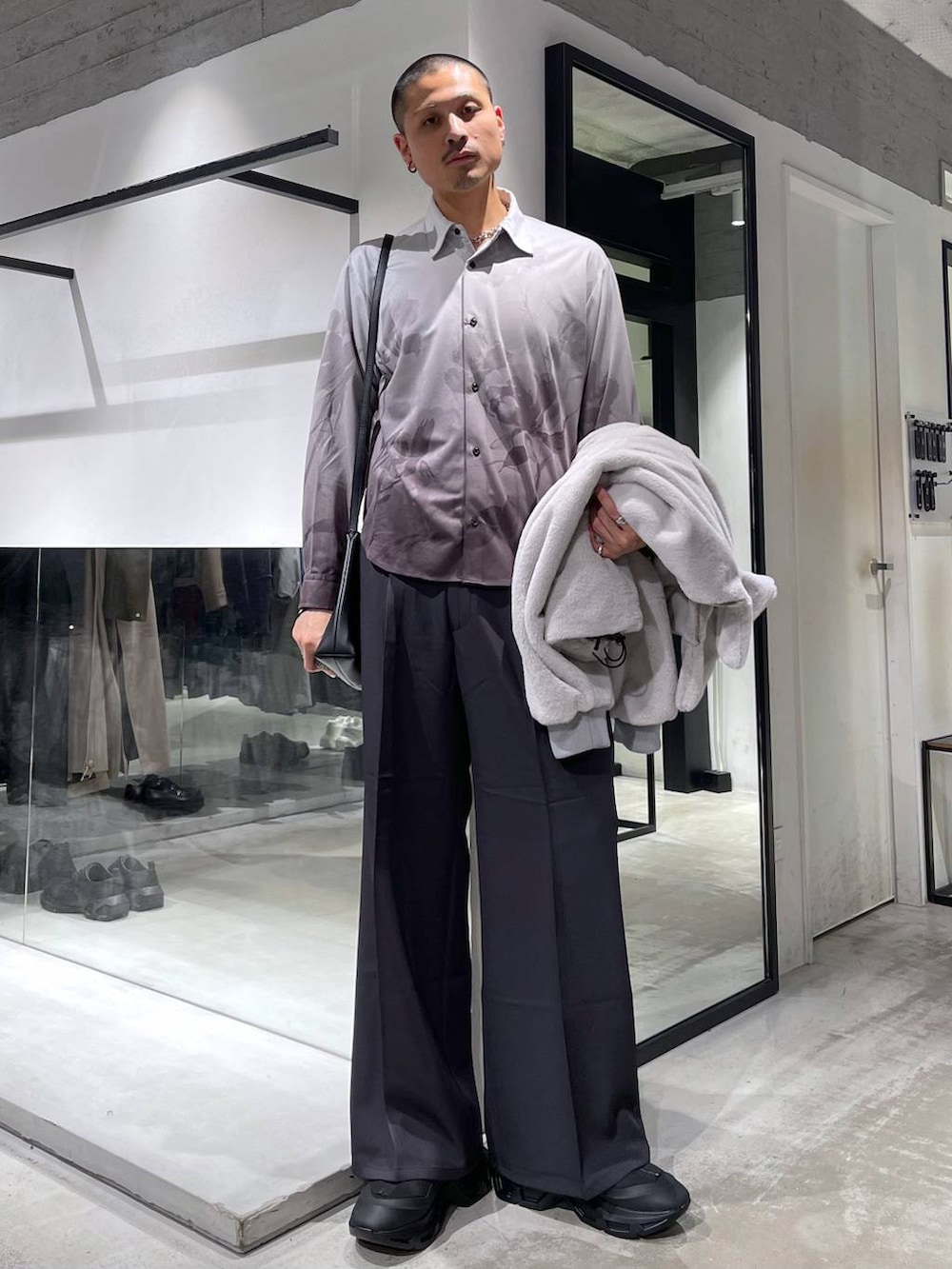 グレー系のブルゾン、グレー系のスラックス、ブラック系のショルダーバッグを着用したメンズの冬コーディネートの5枚目の写真