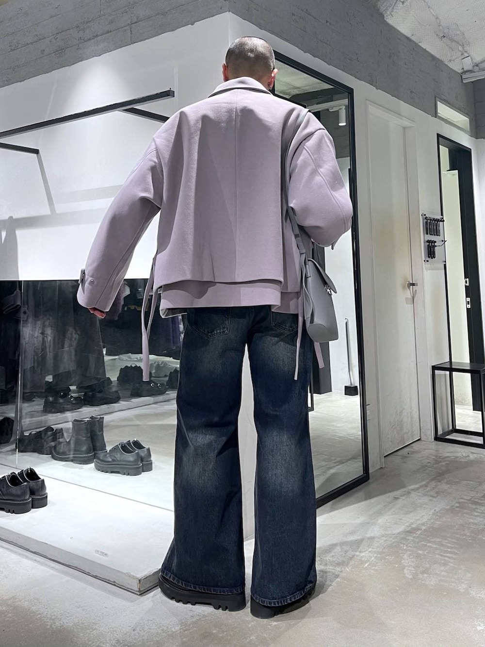 パープル系のブルゾン、ブルー系のデニムパンツ、ブラック系のドレスシューズを着用したメンズの秋コーディネートの3枚目の写真