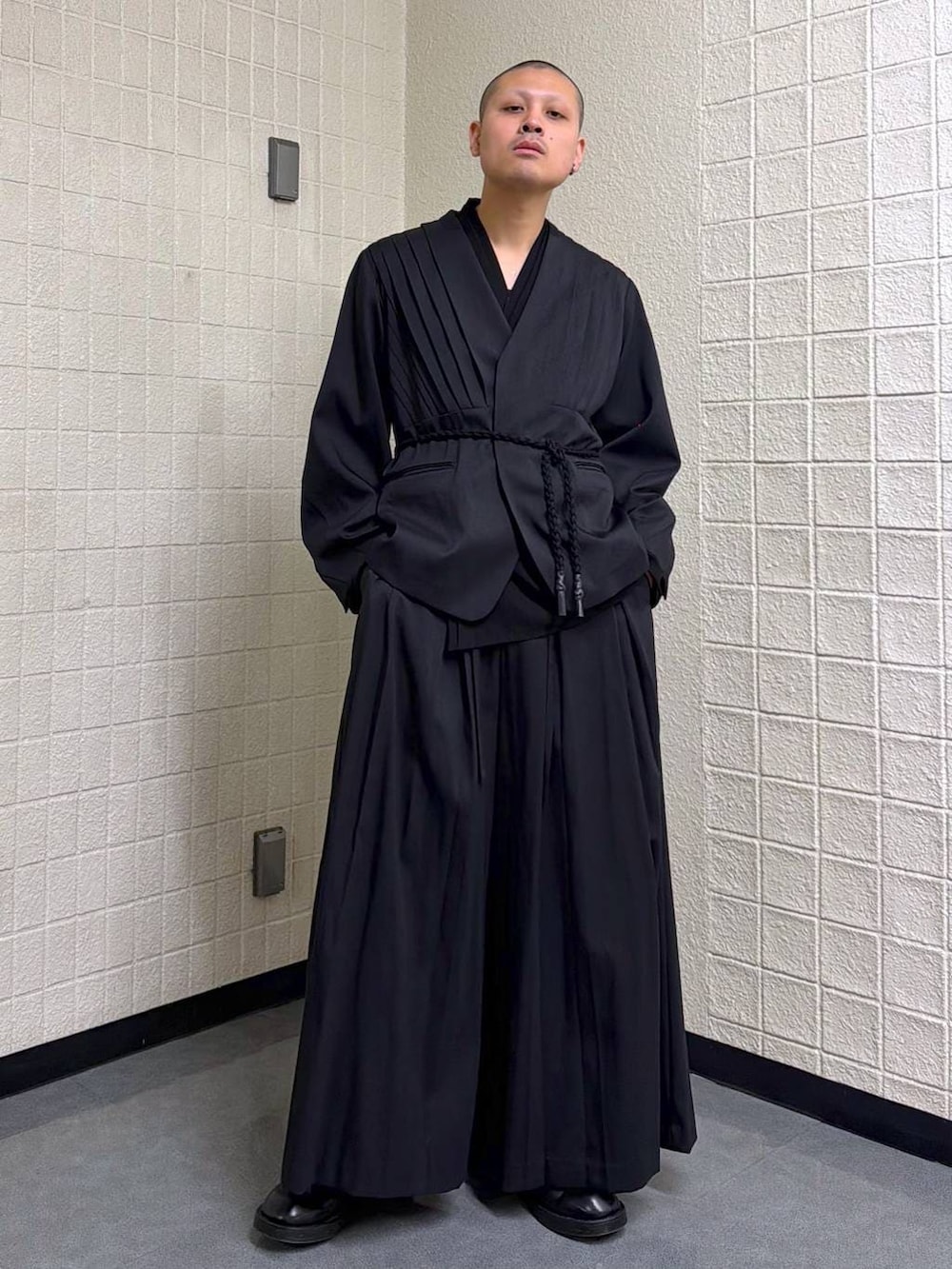 ブラック系のノーカラージャケットを着用したメンズの春コーディネートの2枚目の写真