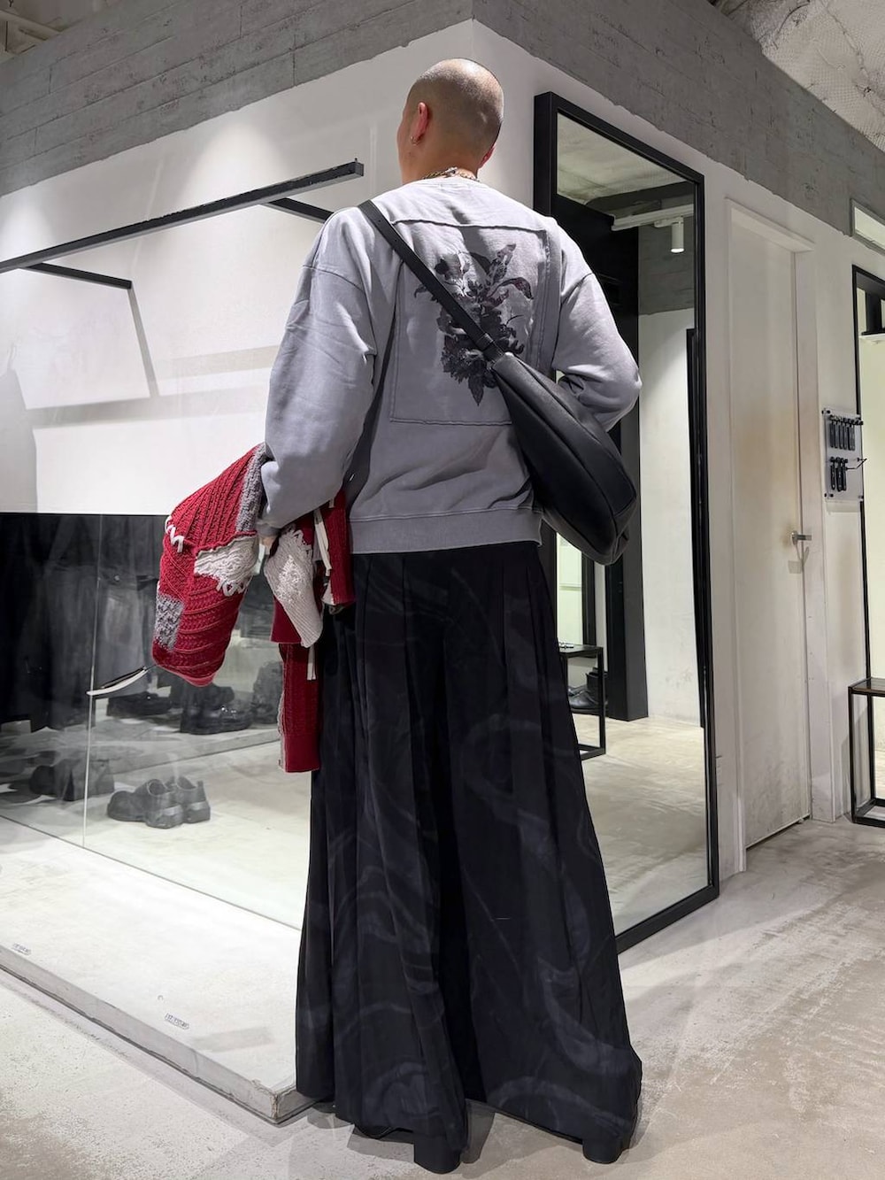 ブラック系のブルゾン、グレー系のその他パンツ、レッド系のカーディガン/ボレロを着用したメンズの冬コーディネートの7枚目の写真