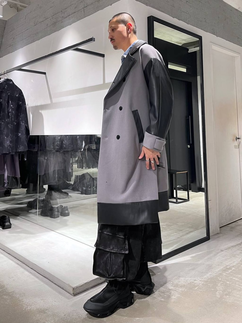グレー系のトレンチコート、ブルー系のカーディガン/ボレロ、ブラック系のトートバッグを着用したメンズの冬コーディネートの2枚目の写真