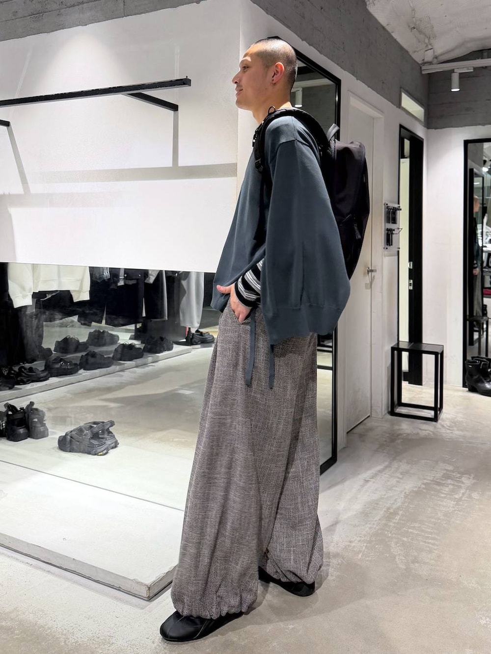 ブラック系のバックパック/リュック、グレー系のスラックス、グリーン系のカーディガン/ボレロを着用したメンズの春コーディネートの3枚目の写真