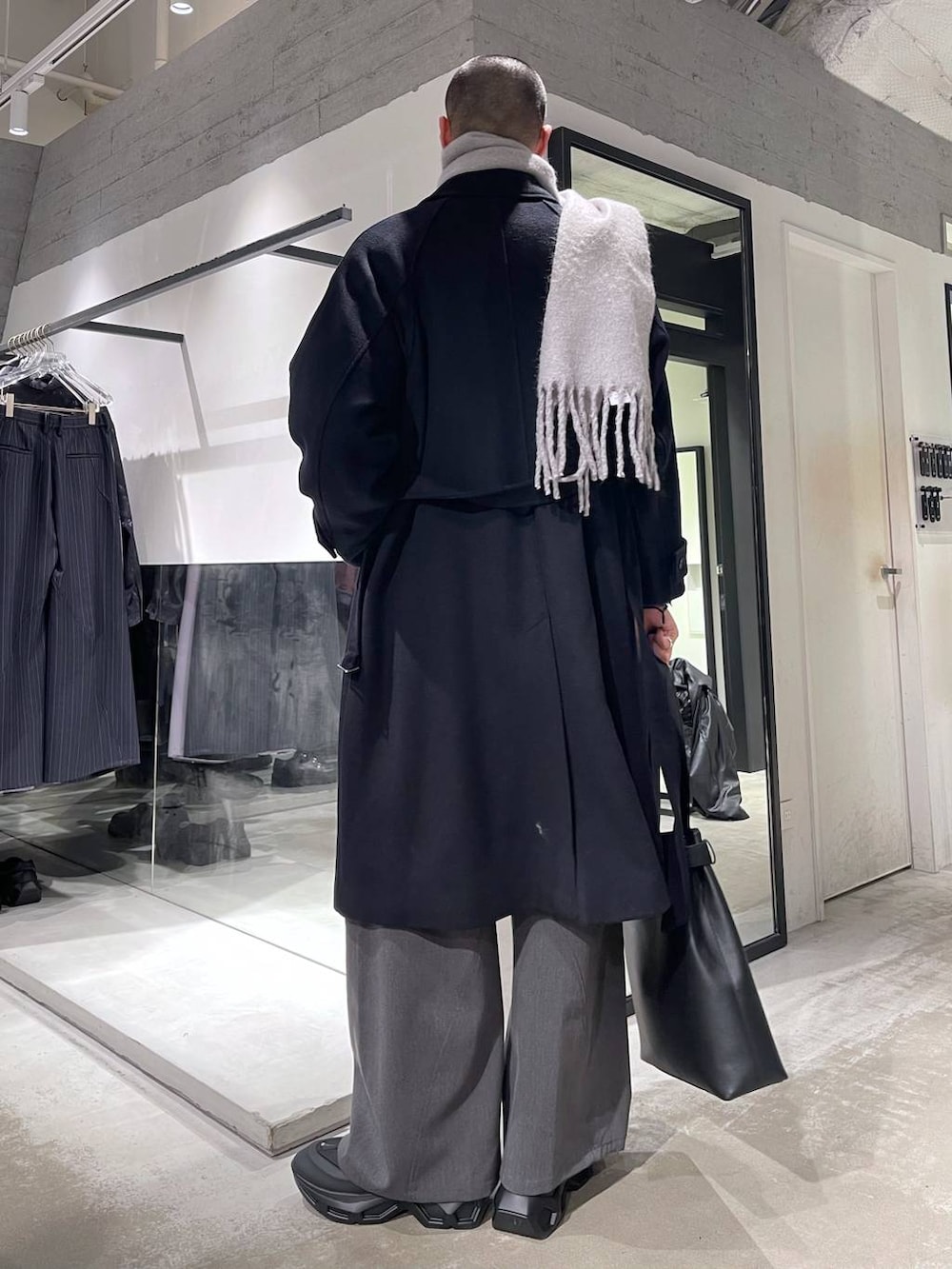 ブラック系のステンカラーコート、ブルー系のカーディガン/ボレロ、ブラック系のトートバッグを着用したメンズの冬コーディネートの3枚目の写真