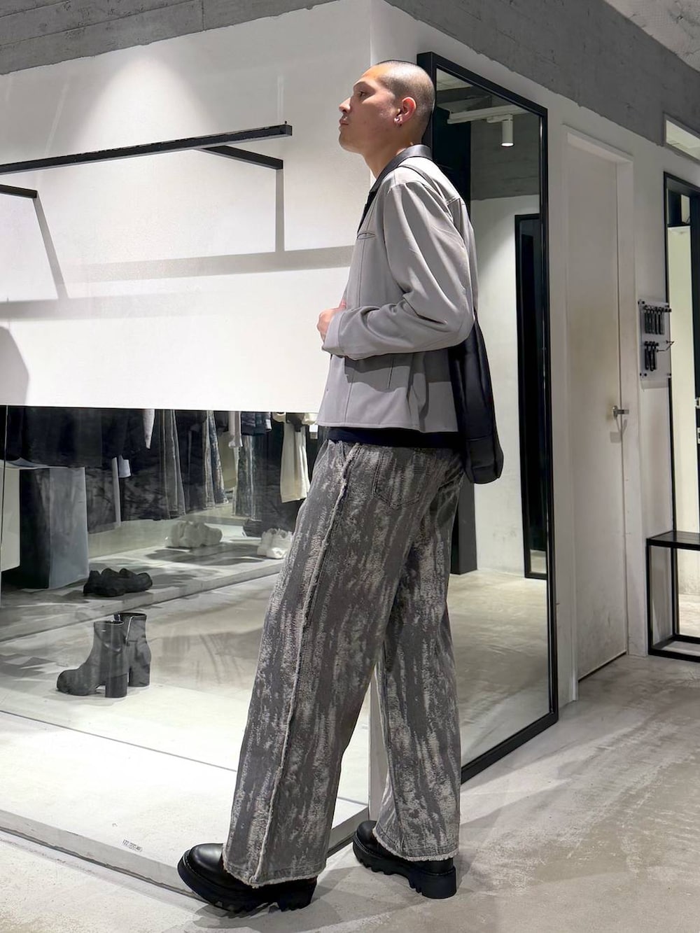 ブラック系のドレスシューズ、ブラック系のショルダーバッグ、グレー系のデニムパンツを着用したメンズの春コーディネートの2枚目の写真