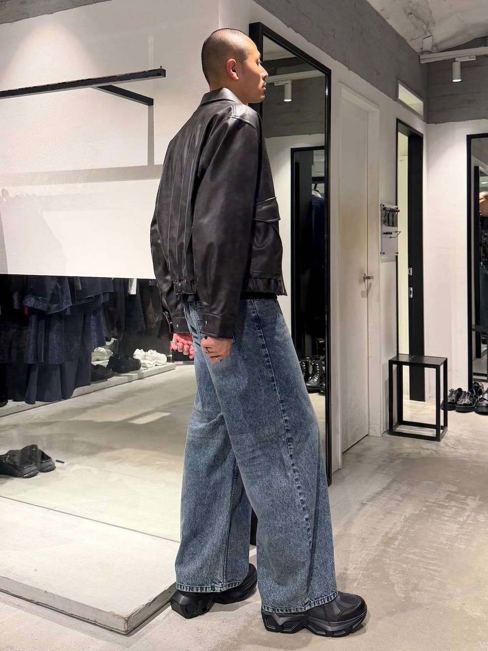 ブルー系のデニムパンツ、ブラック系のTシャツ/カットソー、ブラック系のスニーカーを着用したメンズの秋コーディネートの4枚目の写真