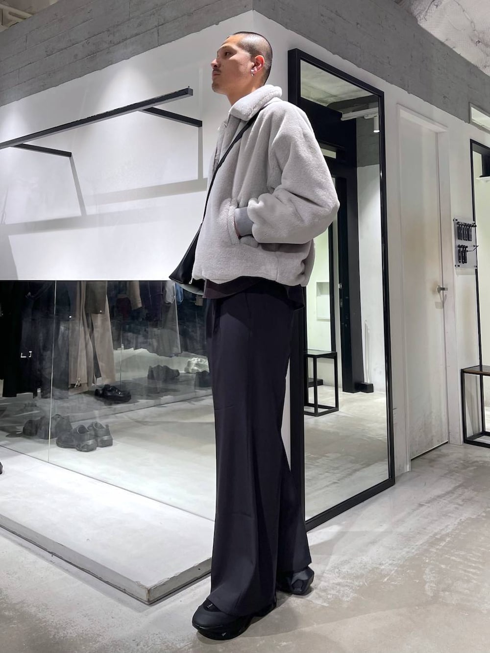 グレー系のブルゾン、グレー系のスラックス、ブラック系のショルダーバッグを着用したメンズの冬コーディネートの2枚目の写真