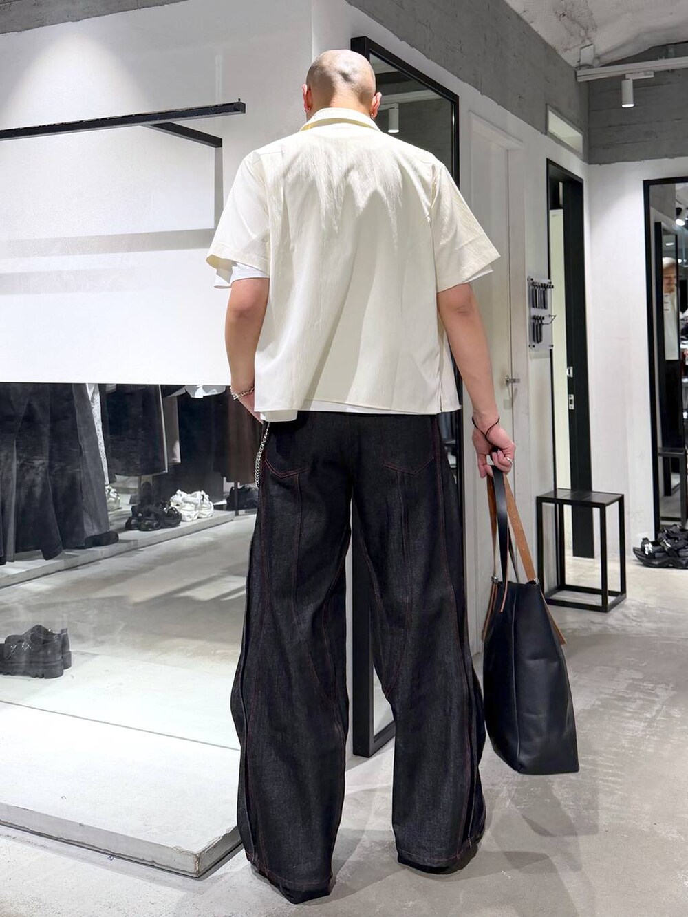 ブラック系のデニムパンツ、ブラック系のトートバッグ、ホワイト系のシャツ/ブラウスを着用したメンズの夏コーディネートの3枚目の写真