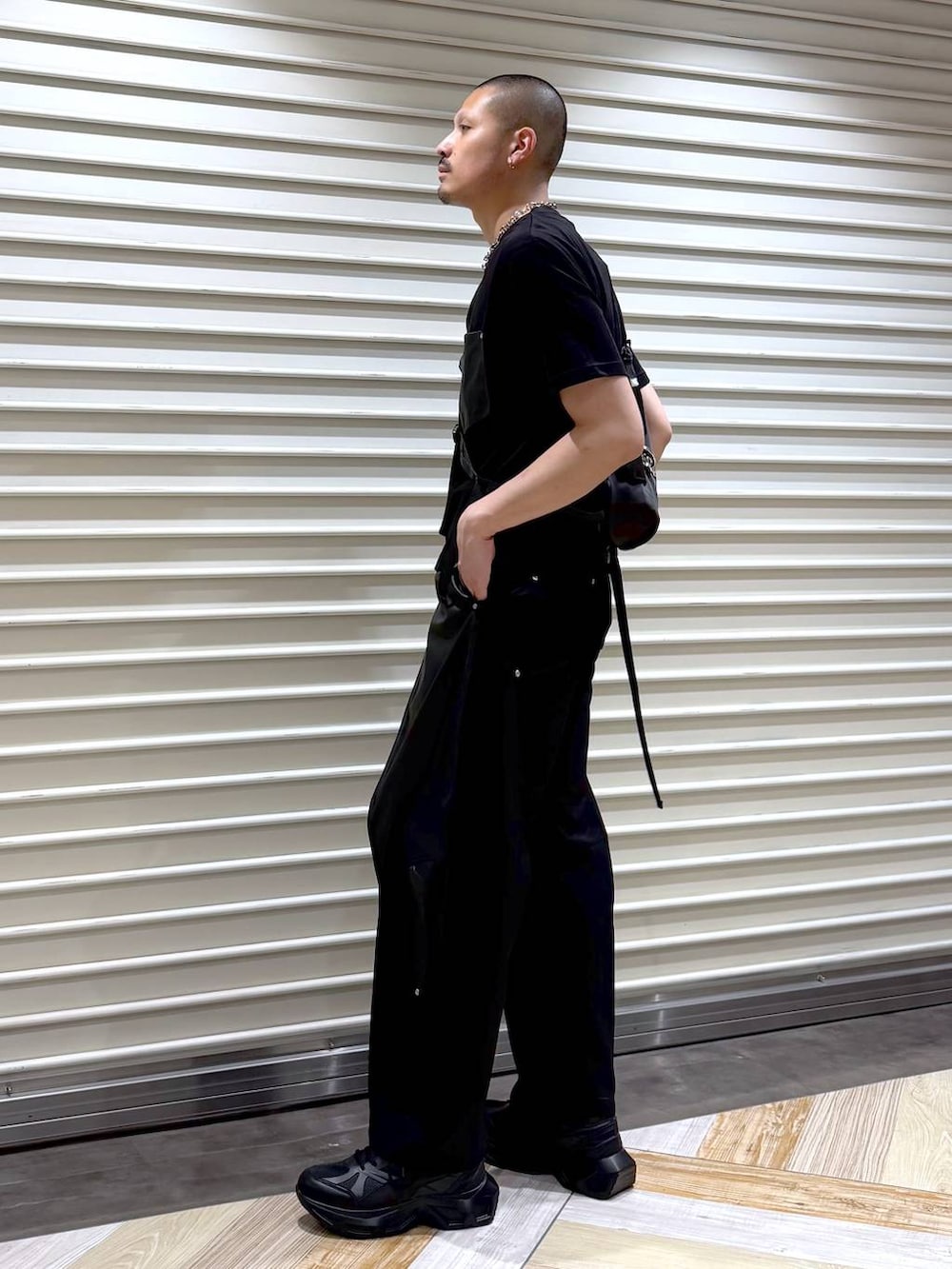 ブラック系のスラックス、ブラック系のTシャツ/カットソー、ブラック系のスニーカーを着用したメンズの夏コーディネートの2枚目の写真