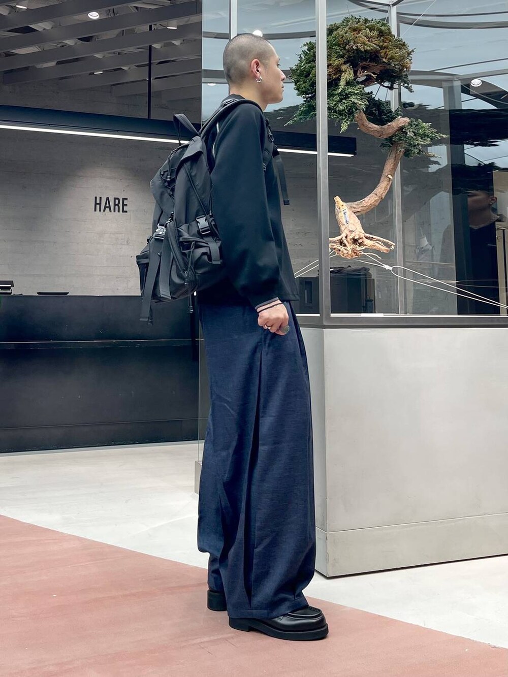 ブルー系のスラックス、ブラック系のローファー、ブラック系のバックパック/リュックを着用したメンズの秋コーディネートの4枚目の写真