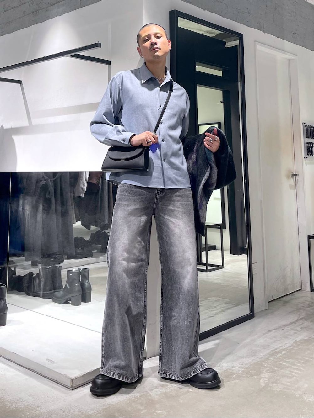 グレー系のデニムパンツ、ブラック系のローファー、ブラック系のショルダーバッグを着用したメンズの冬コーディネートの5枚目の写真