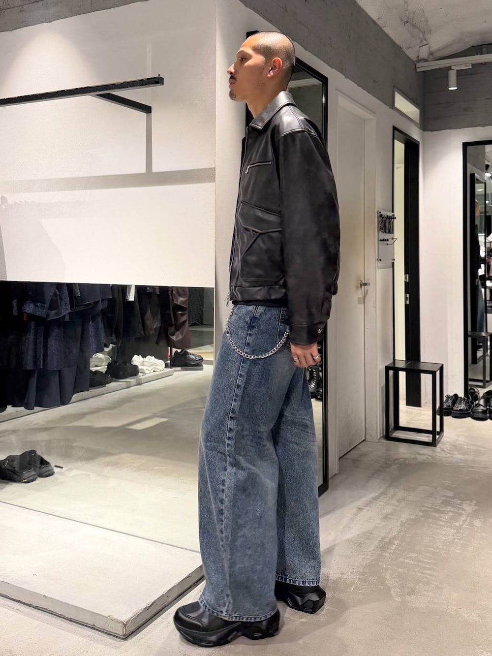 ブルー系のデニムパンツ、ブラック系のTシャツ/カットソー、ブラック系のスニーカーを着用したメンズの秋コーディネートの2枚目の写真