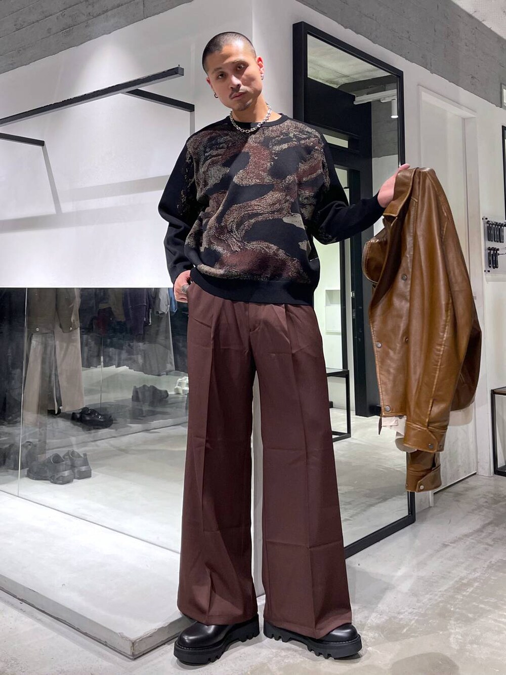 レッド系のスラックス、ブラック系のドレスシューズ、ブラック系のニット/セーターを着用したメンズの冬コーディネートの5枚目の写真