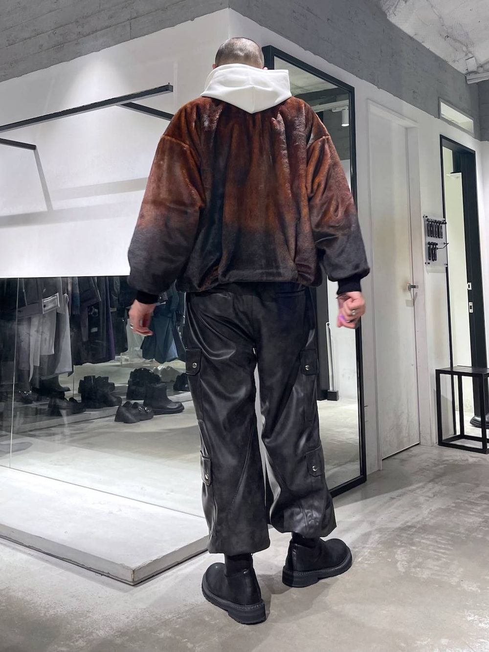 オレンジ系のブルゾン、グレー系のカーゴパンツ、ブラック系のブーツを着用したメンズの秋コーディネートの3枚目の写真