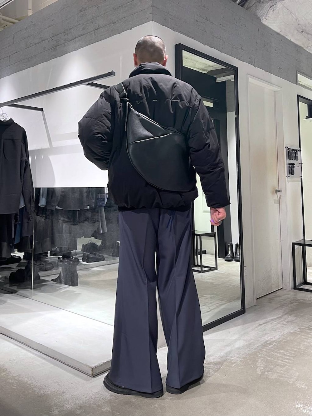 ブラック系のダウンジャケット/コート、ブラック系のブーツ、ブラック系のショルダーバッグを着用したメンズの冬コーディネートの3枚目の写真