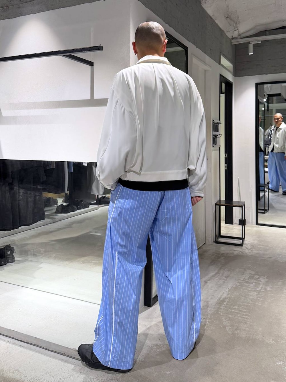 ホワイト系のブルゾン、ブルー系のスラックス、ブラック系のニット/セーターを着用したメンズの春コーディネートの3枚目の写真