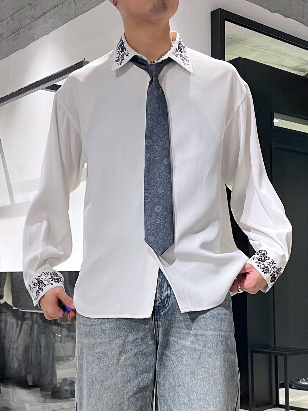 ブルー系のネクタイ、ブラック系のカーディガン/ボレロ、ブルー系のデニムパンツを着用したメンズの冬コーディネートの6枚目の写真