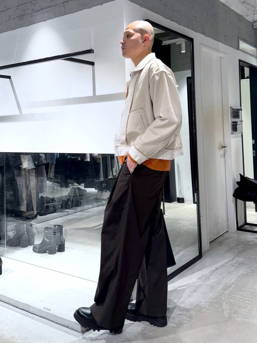 ブラック系のドレスシューズ、ブラック系のトートバッグ、オレンジ系のニット/セーターを着用したメンズの冬コーディネートの2枚目の写真